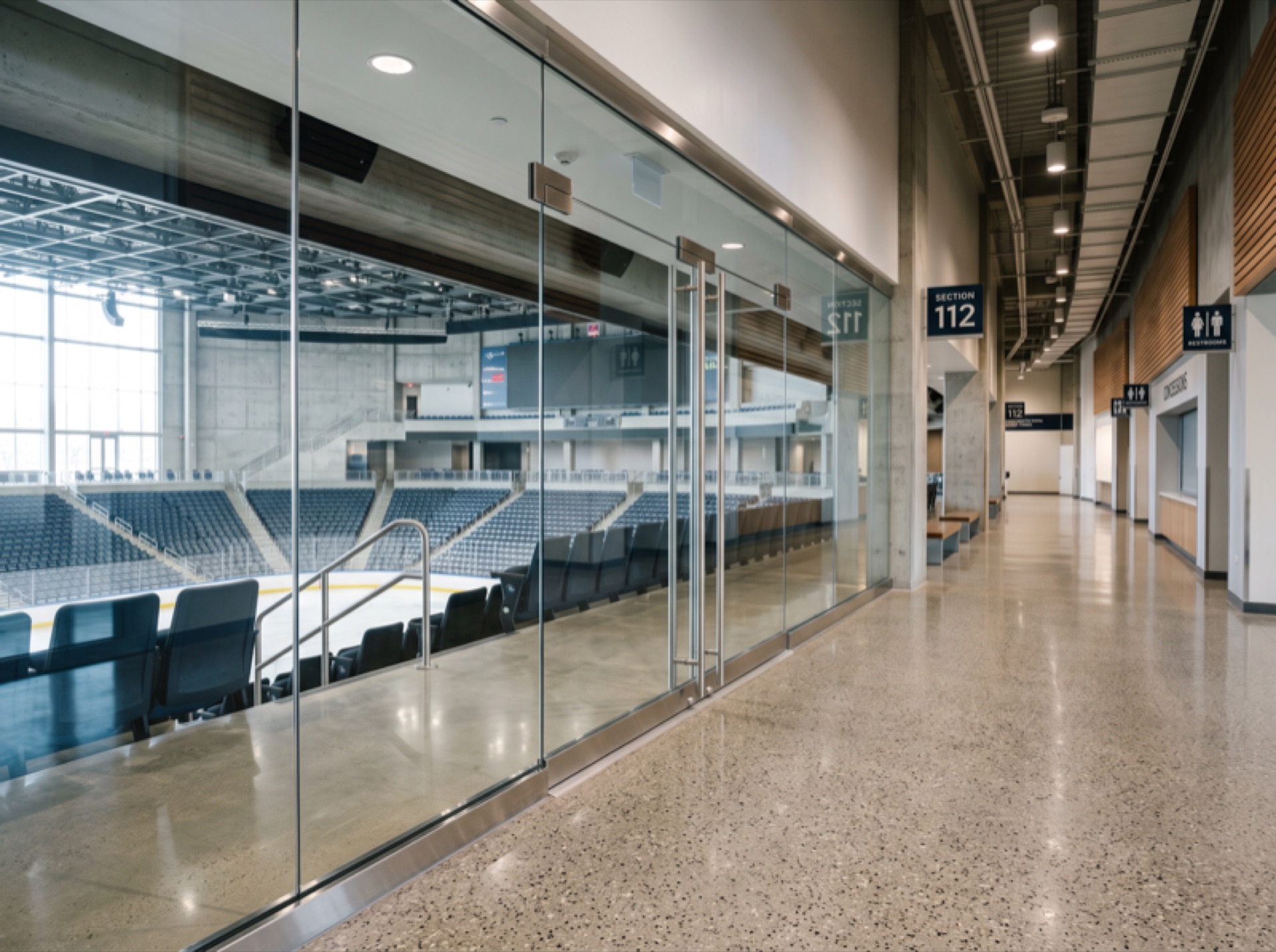 Clean arena concourse glass partition with anti-graffiti film — pristine transparent surface