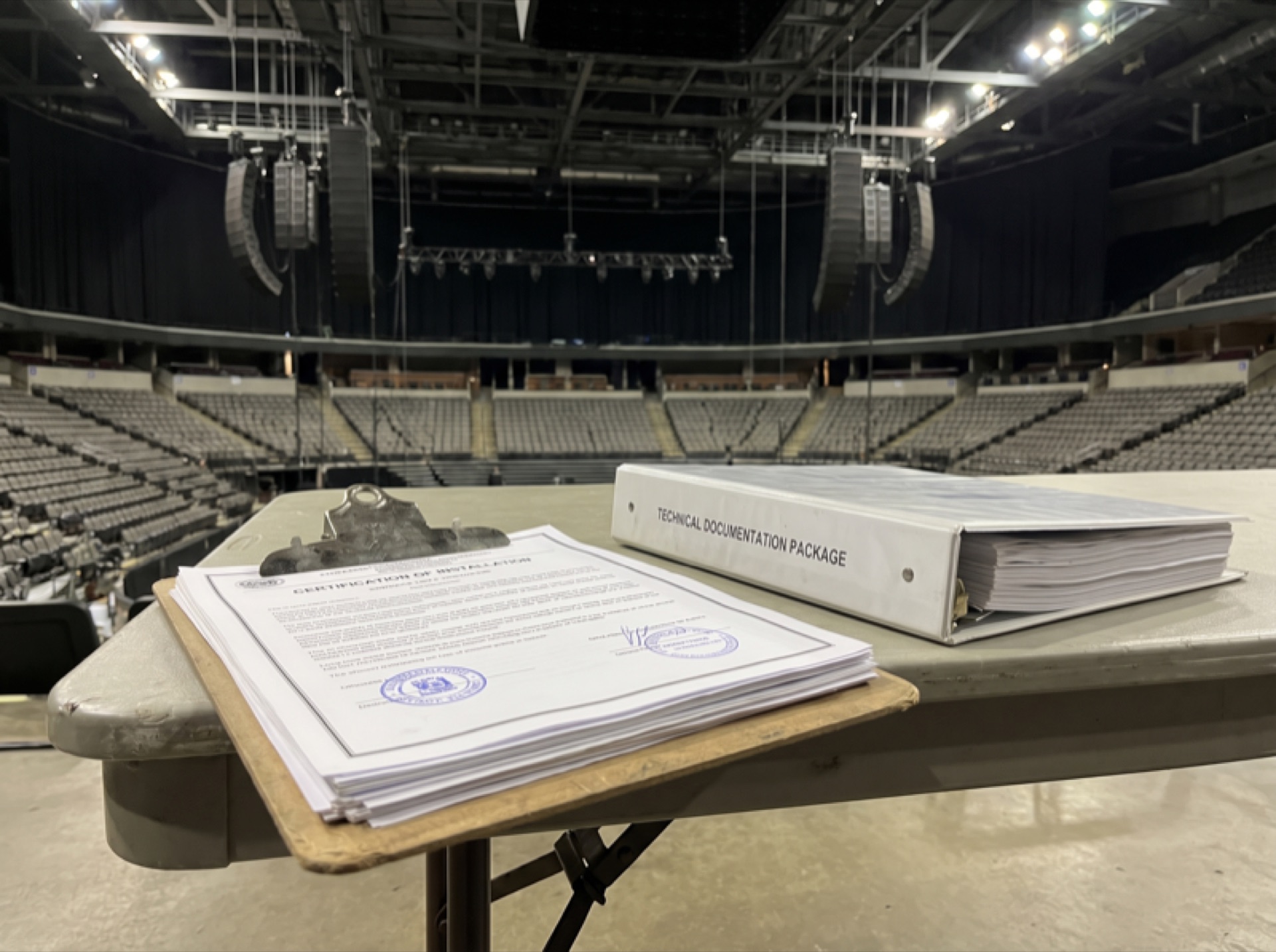 Certification document and technical documentation on a clipboard in an arena setting