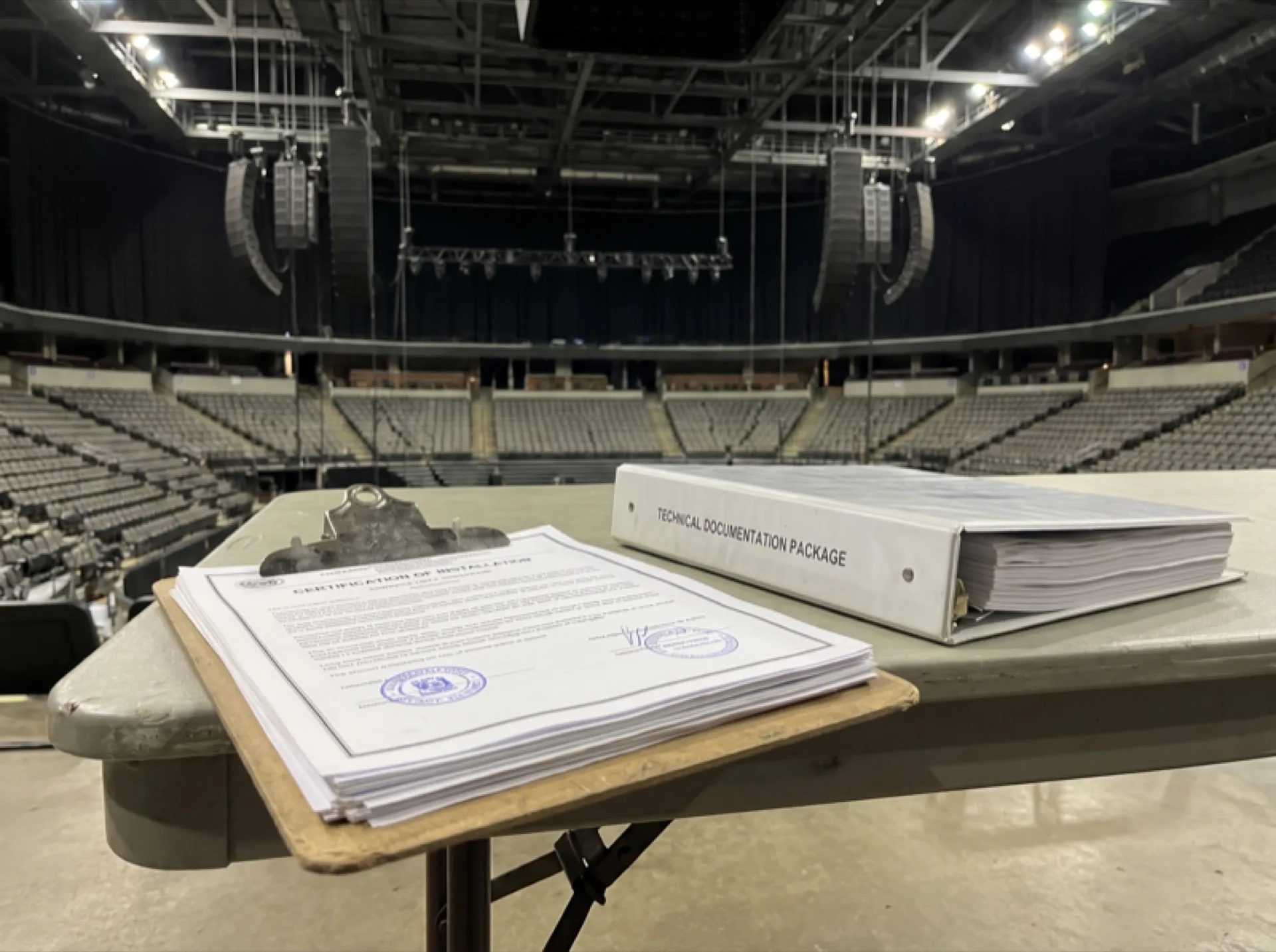 Certification document and technical documentation on a clipboard in an arena setting